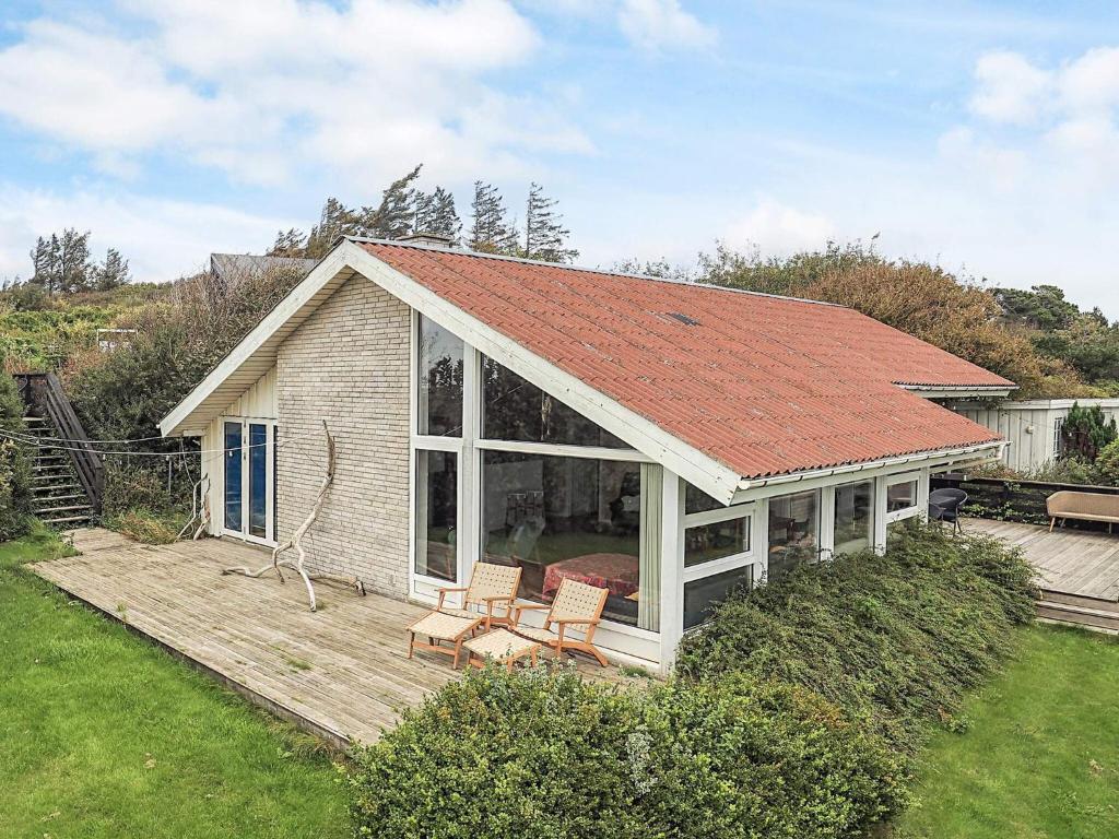 ein Haus mit einer Terrasse mit zwei Stühlen und einem Dach in der Unterkunft 4 person holiday home in Struer in Struer