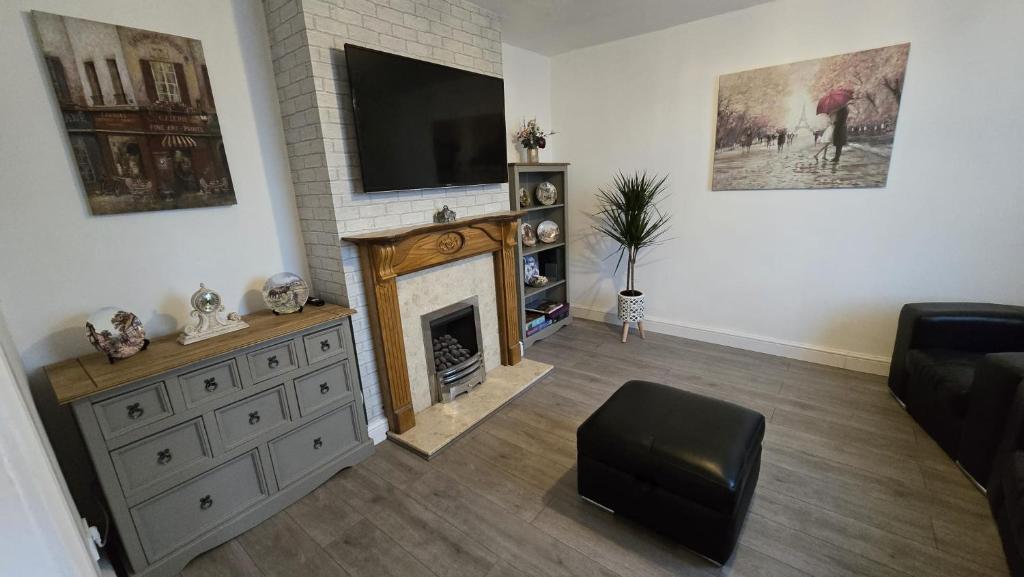 ein Wohnzimmer mit einem Kamin und einem Flachbild-TV in der Unterkunft Ecclesfield Cottage - Two Bedrooms in Sheffield near Peak District with fast Wi-Fi, off-street parking and garden in Ecclesfield