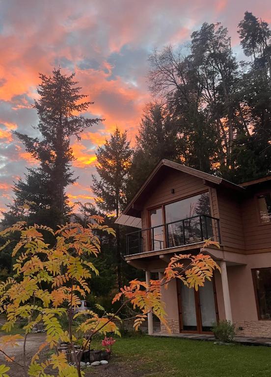 a house with a sunset in the background at CasaSur-37Robles-2 in Villa La Angostura