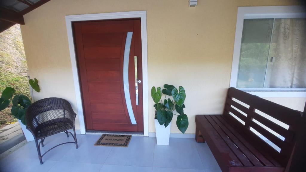 a door of a house with a bench and a plant at Quarto Aconchegante Teresópolis Refúgio Cristão in Teresópolis