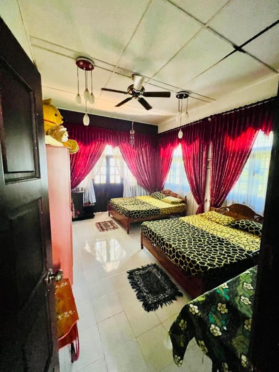 a bedroom with two beds and red curtains at A Home Away B&B in Kiribatkumbura
