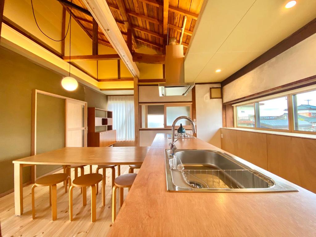 cocina con fregadero y mesa de madera en 広い縁側とタタミの部屋に天井吹抜けのオープンキッチンがある一軒家でキッチンやバスルームは最新設備, en Komoro