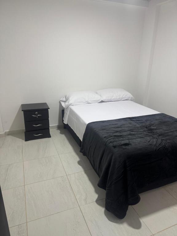 ein Schlafzimmer mit einem Bett mit einer schwarzen Decke und einem Nachttisch in der Unterkunft Bulevar Santa Rosa, apartamento nuevo y acogedor in Santa Rosa de Cabal
