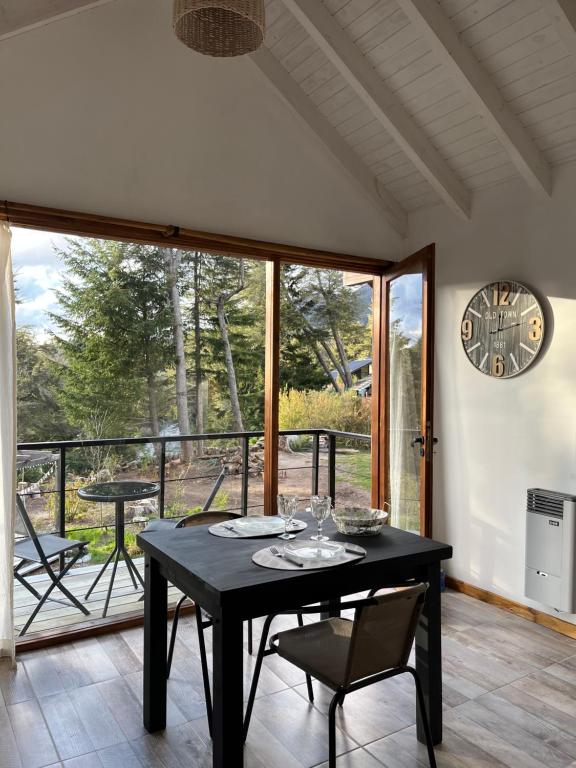 una sala da pranzo con tavolo, sedie e orologio di CasaSur-37Robles-2 a Villa La Angostura