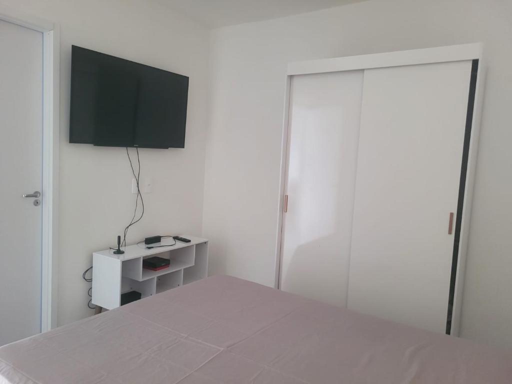 une chambre blanche avec un lit et une télévision au mur dans l'établissement Ap em Juazeiro do Norte com dois quartos com cama de casal e ar condicionado, à Juazeiro do Norte