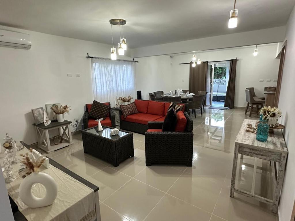 ein Wohnzimmer mit einem roten Sofa und einem Tisch in der Unterkunft Pretty Family house! In Punta Cana in Punta Cana