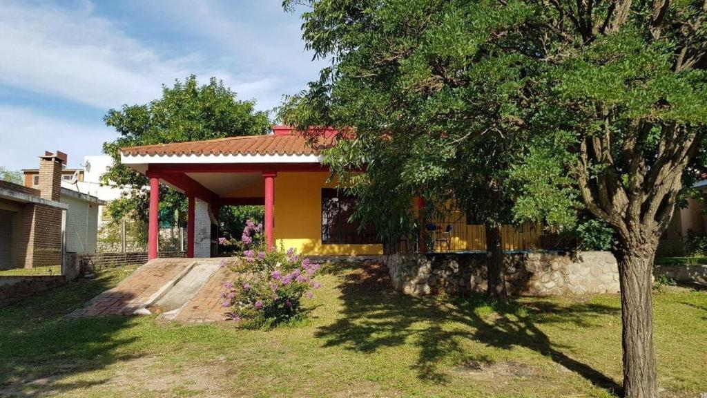 ein kleines gelbes Haus mit einem Baum im Hof in der Unterkunft Alojamiento Arroyo de los Patos in Arroyo de Los Patos