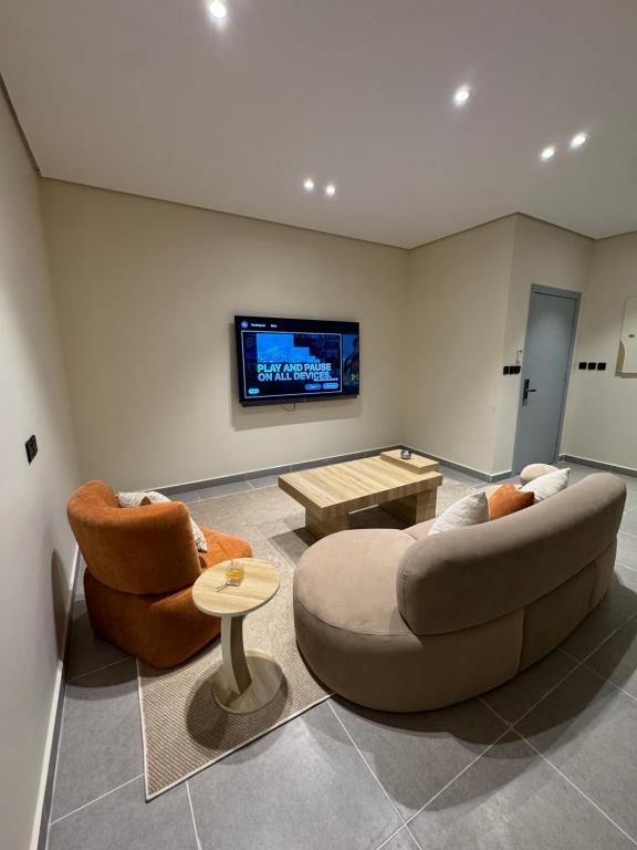a living room with two couches and a tv at luxury apartment in Al-ʿUla