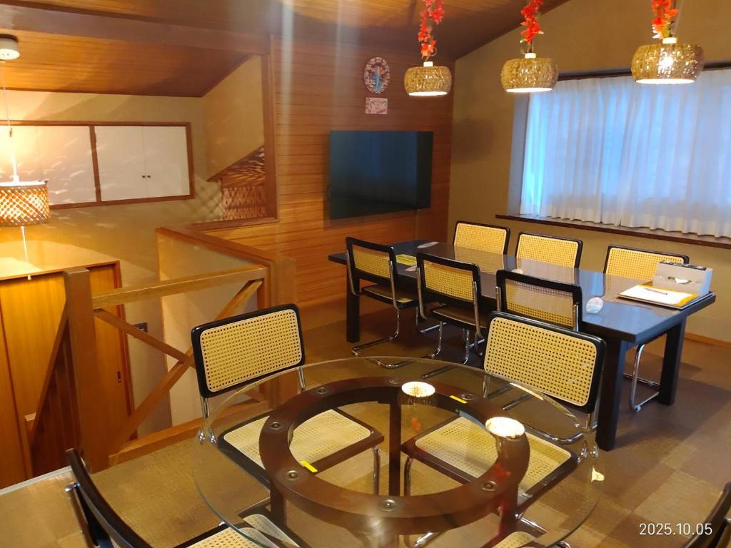 ein Esszimmer mit Tisch und Stühlen und einem Fernseher in der Unterkunft ファミーユグループ城ケ崎店 海音Umine in Ito