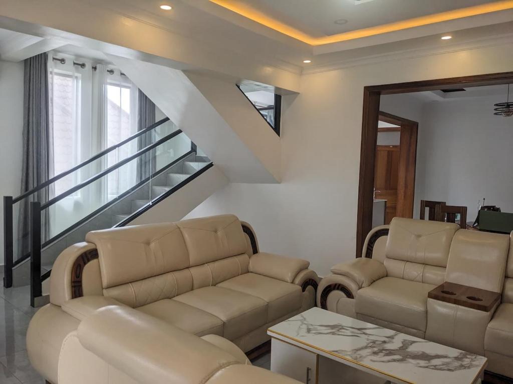 a living room with leather furniture and a staircase at Luxury Mansion for Rent in Kigali
