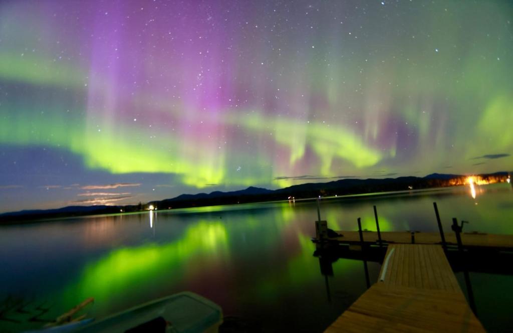 een poollicht boven een meer 's nachts met een boot bij Suite on the Bay in Marsh Lake