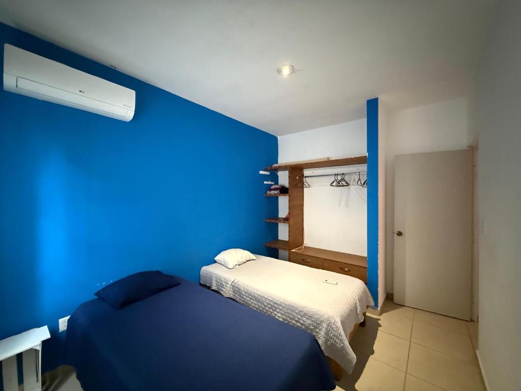 a bedroom with a blue wall and a bed at Pez Vela in Puerto Morelos