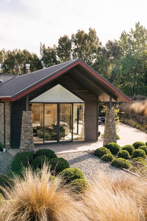a house with a large window and some bushes at Cardrona Alpine Villa by Sothebys Luxury Rental Homes in Cardrona