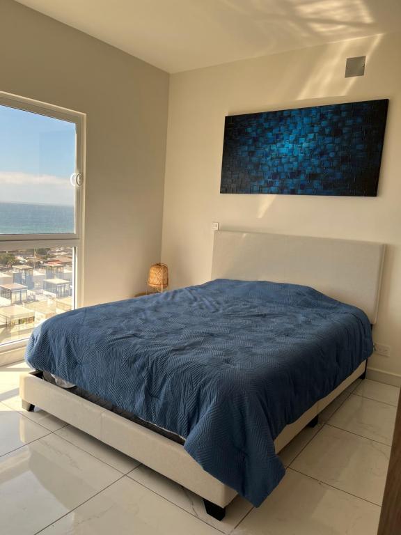 a bedroom with a blue bed and a large window at Rosarito Sol y Mar Getaway in Rosarito Beach