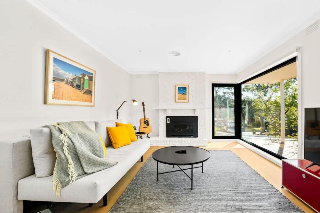 Una sala de estar con un sofá blanco y una mesa. en Relaxed Family Coastal Retreat in Leafy Mt Martha, en Mount Martha