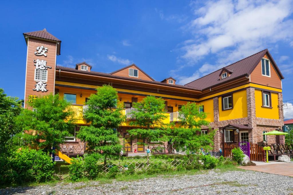 un gran edificio amarillo con una torre de reloj en The Anderson Manor Hotel, en Ruisui