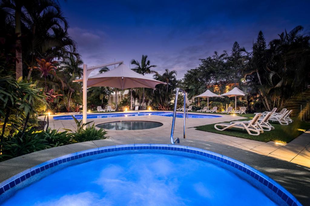 a swimming pool at night with an umbrella and chairs at Noosa Harbour Resort in Noosa Heads