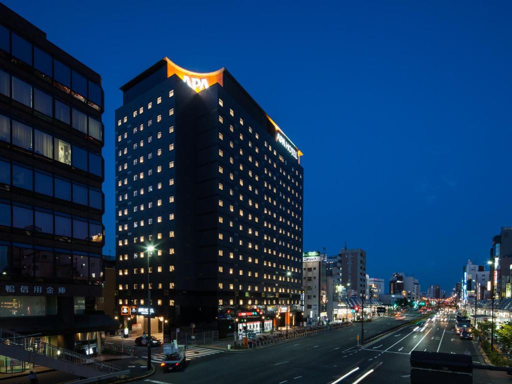 a tall building on a city street at night at APA Hotel Sugamo Ekimae in Tokyo