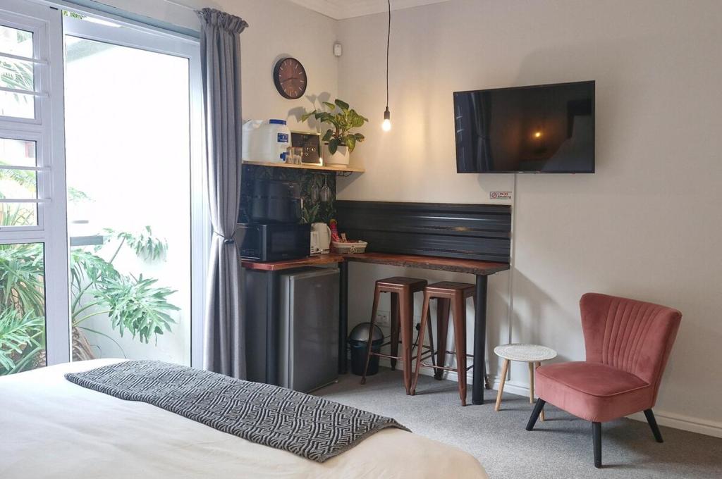 a bedroom with a bed and a bar with a tv at The Little Homestead in Gqeberha