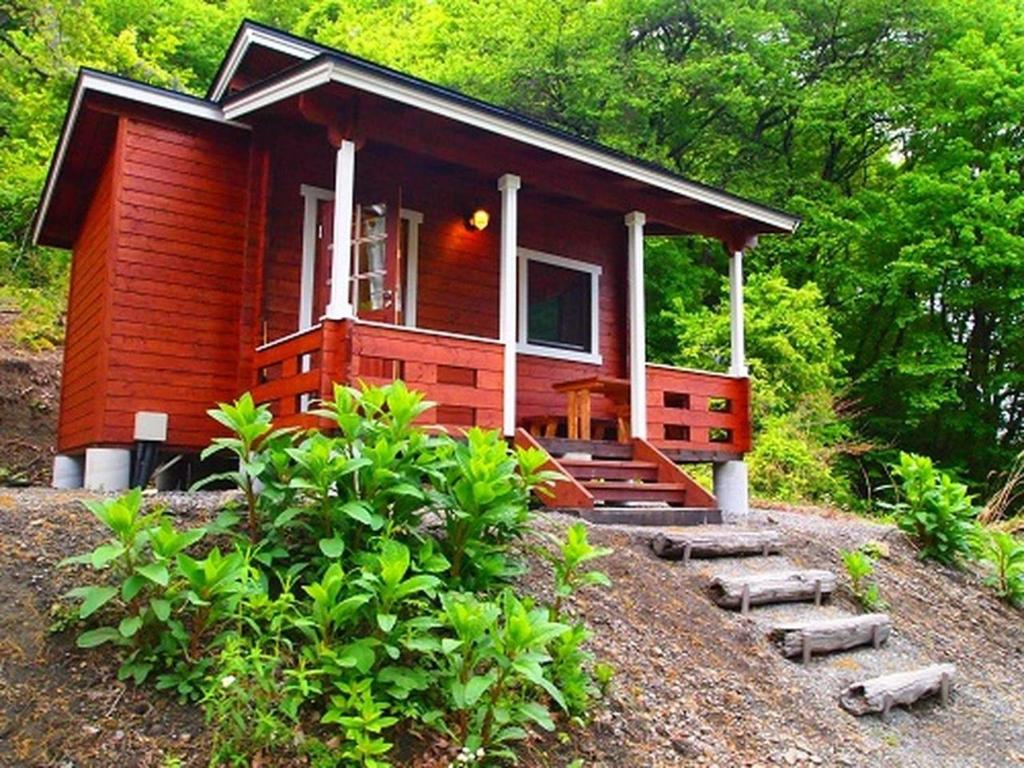 une petite maison rouge avec un porche et un escalier y menant dans l'établissement Foresters Village Kobitto Southern Alps Camp Field - Vacation STAY 78097v, à Shirasu
