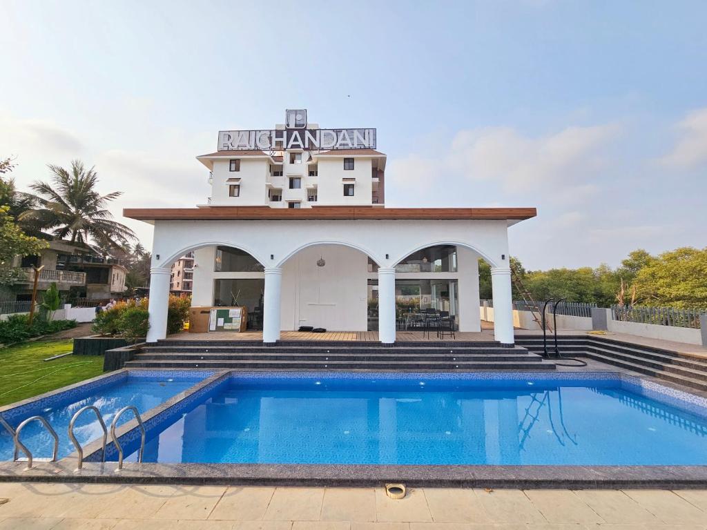 a hotel with a swimming pool in front of a building at Chic 1BHK Apartment - Pool, Gym, Amenities Near Candolim Beach in Candolim