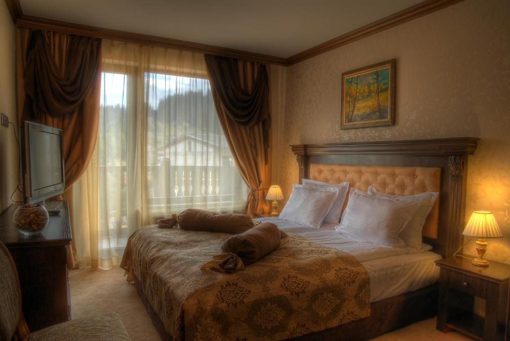 a bedroom with a large bed and a television at Hotel Iva & Elena in Pamporovo
