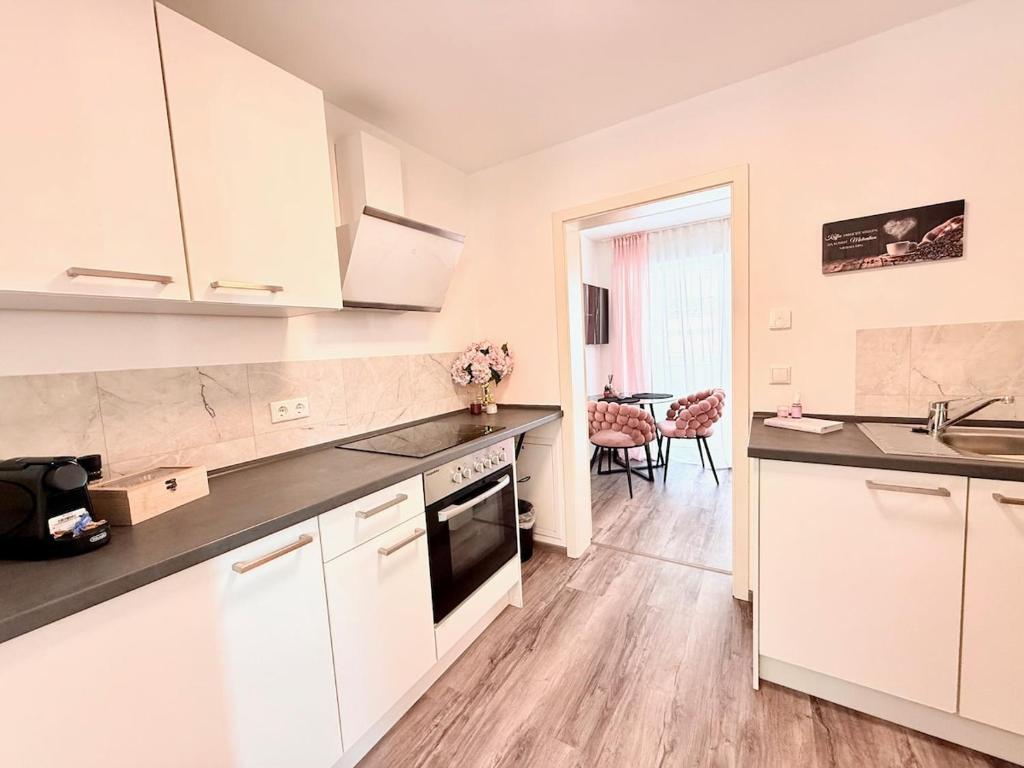 Una cocina con gabinetes blancos y encimeras negras. en App Balkon Amazon Prime Zentrumsnah Self Checkin, en Augsburg