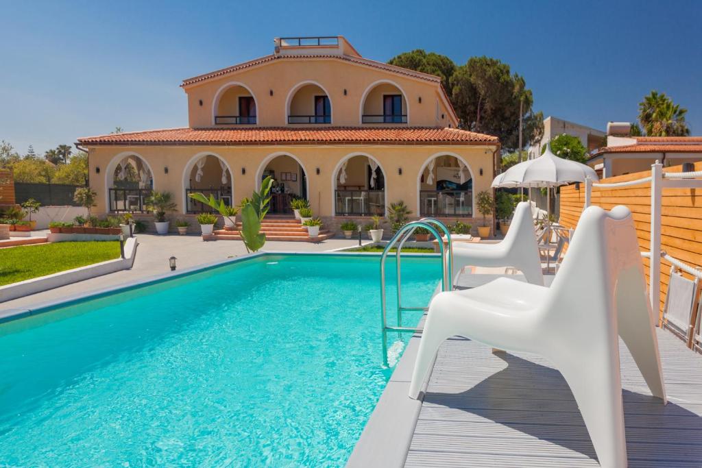 a villa with a swimming pool and a house at Villa Sunset B&B/Apartments in Fontane Bianche