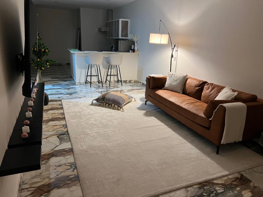sala de estar con sofá marrón y cocina en Six countries apartments, en Al Khīrān