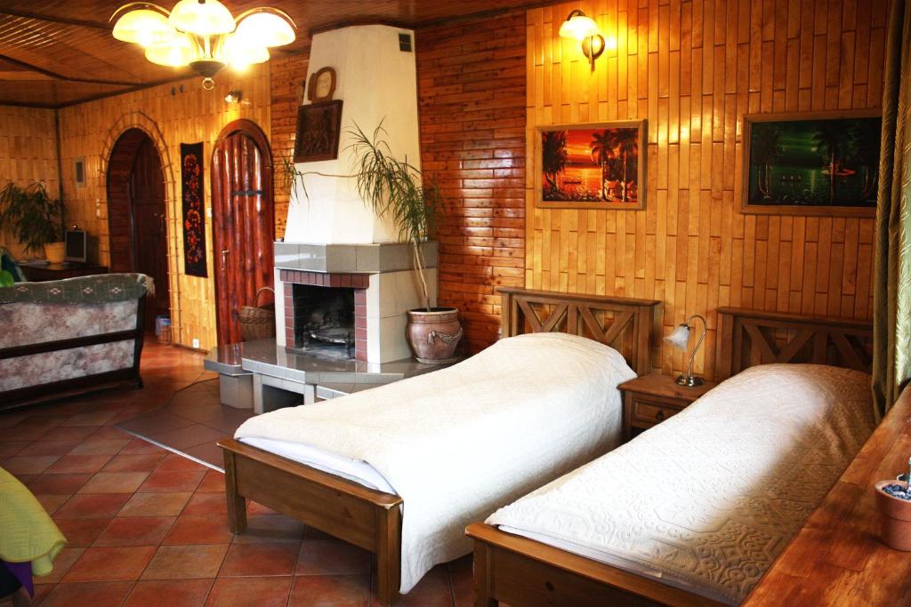 two beds in a room with a fireplace at Pokoje Kaja in Jeleniewo