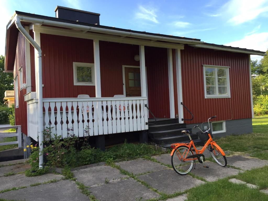 uma casa vermelha com uma bicicleta estacionada em frente em Lingonberry Cottage em Ekenäs
