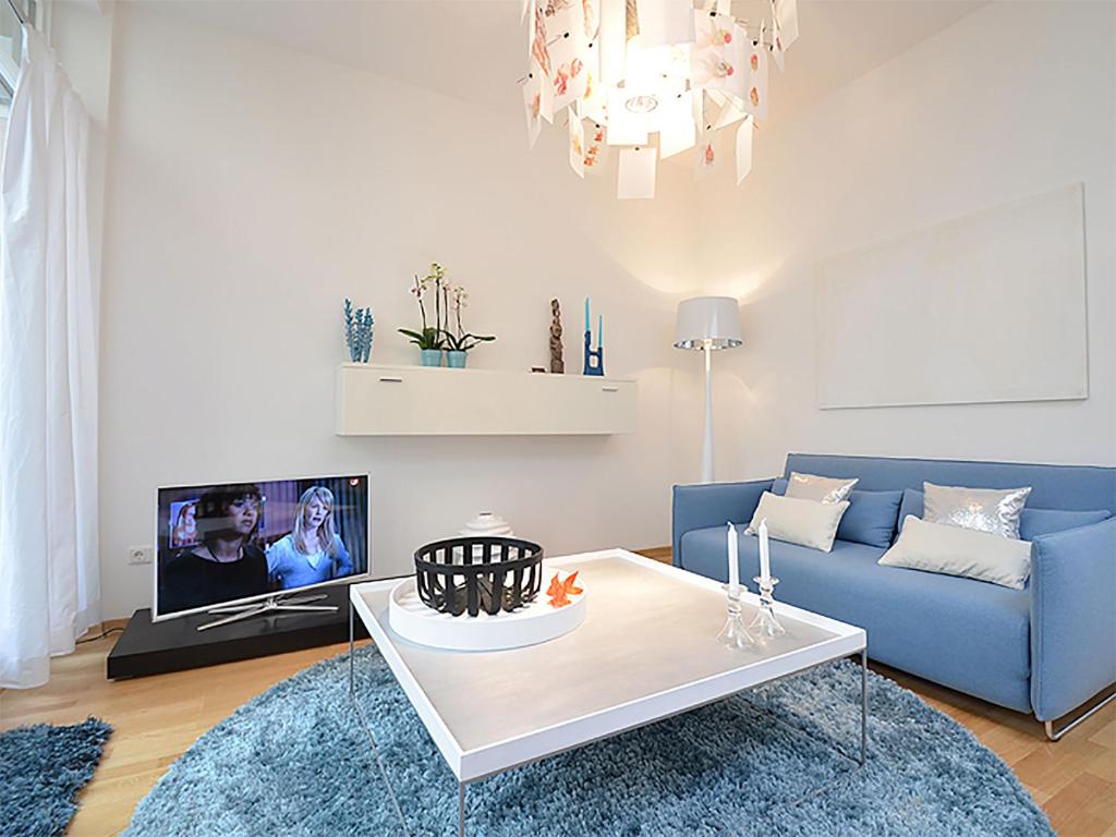 a living room with a blue couch and a table at Como Design-Apartment close to Isar river area - centrally located in Munich