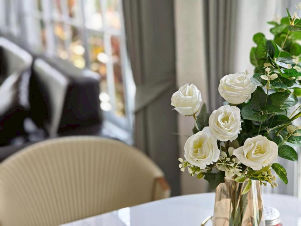 a vase filled with white roses sitting on a table at Canary Pool Villa Bangsaen in Ban Hua Khao Sammuk