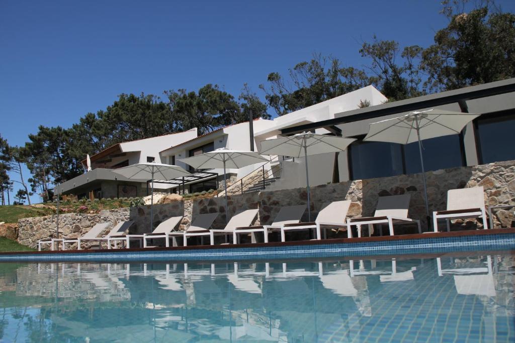una piscina con sedie e ombrelloni accanto a un edificio di Quinta Vale da Roca a Sintra
