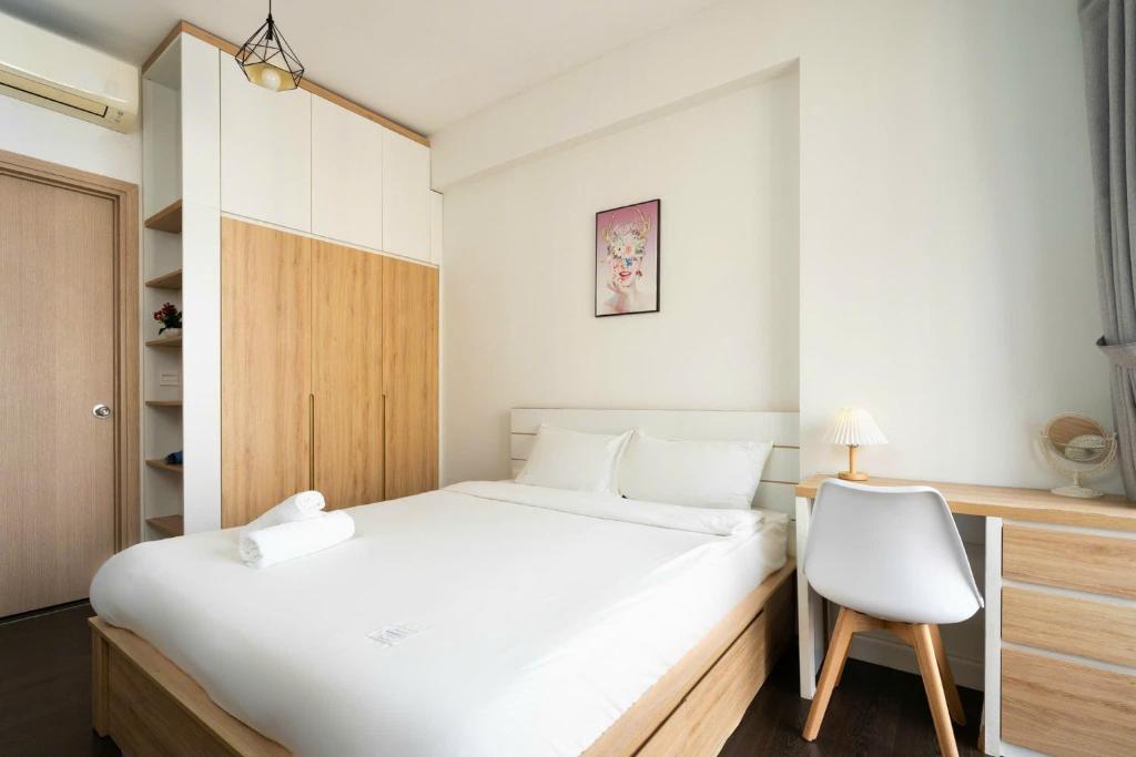 a bedroom with a white bed and a white chair at Rivergate Apartment Central in HCM City in Ho Chi Minh City