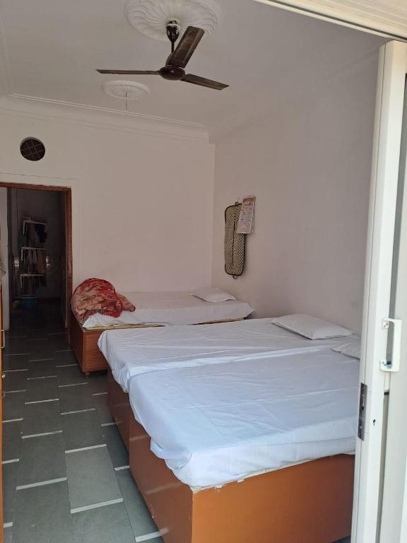 a bedroom with two beds and a ceiling fan at Hotel Narmada Puram in Indore