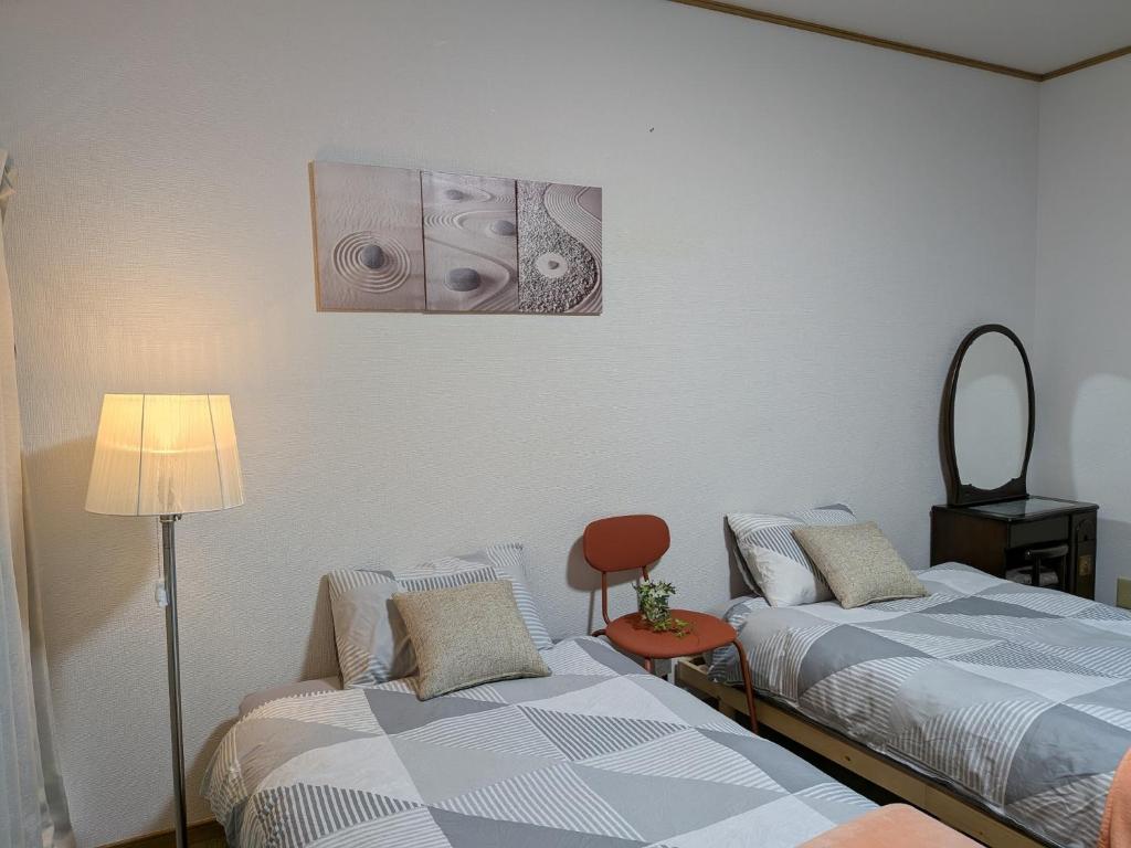 Zimmer mit 2 Betten und einer Lampe in der Unterkunft Apartment Primeira Classe Room 1A - Vacation STAY 54531v in Imaichi