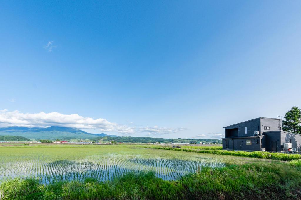 a barn in a field next to a field of grass at Yugen Retreats Furano in Kami-furano