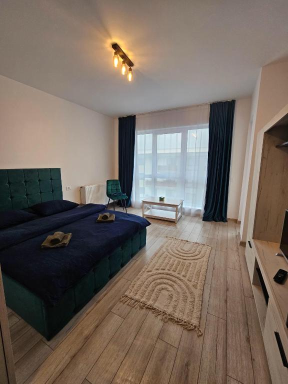 a bedroom with a blue bed and a large window at Studio Râșnov VMP Free Parking in Râşnov