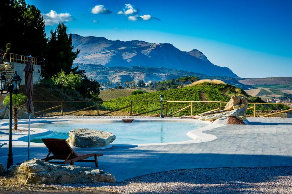ein Pool mit einer Bank und Bergen im Hintergrund in der Unterkunft Agriturismo Antichi Granai in Calatafimi