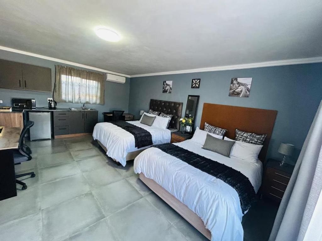 a bedroom with two beds and a kitchen in it at Hope Villa Luxury Accomodation in Odendaalsrus