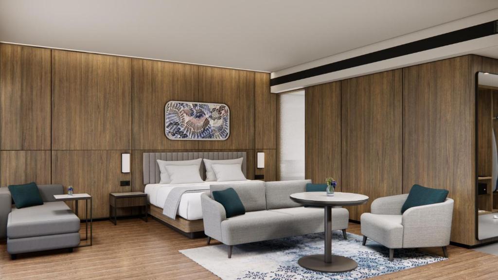 a hotel room with a bed and two chairs at Oakwood Yogyakarta in Jetis