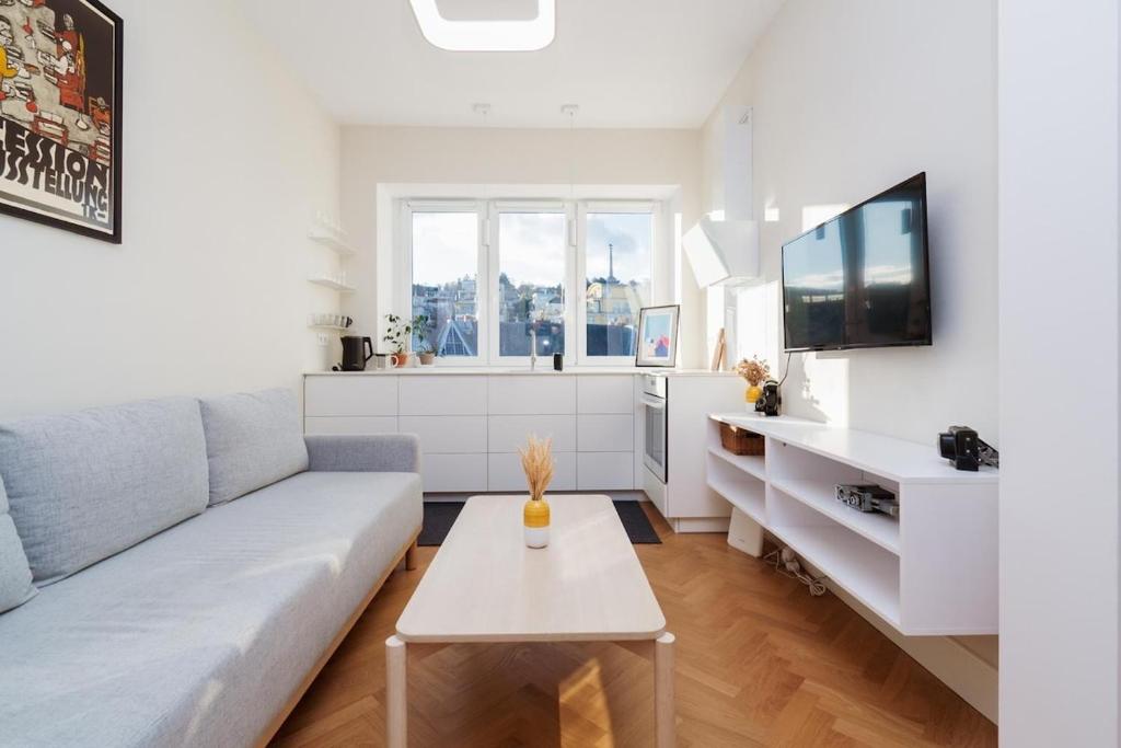 a white living room with a couch and a table at Charming train lines studio in Vinohrady