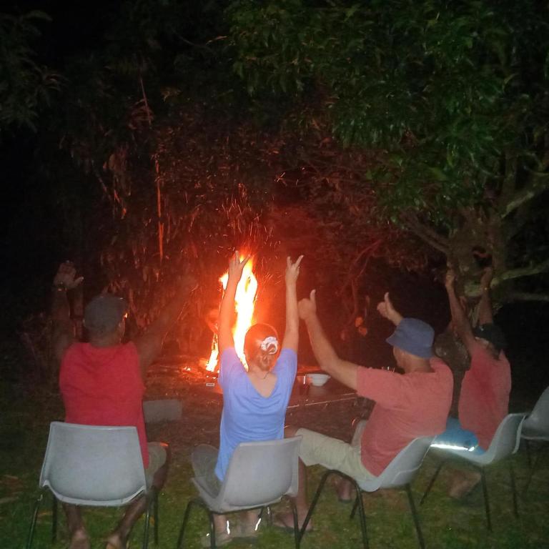 a group of people sitting around a fire at theoutbackhotel in Tonge