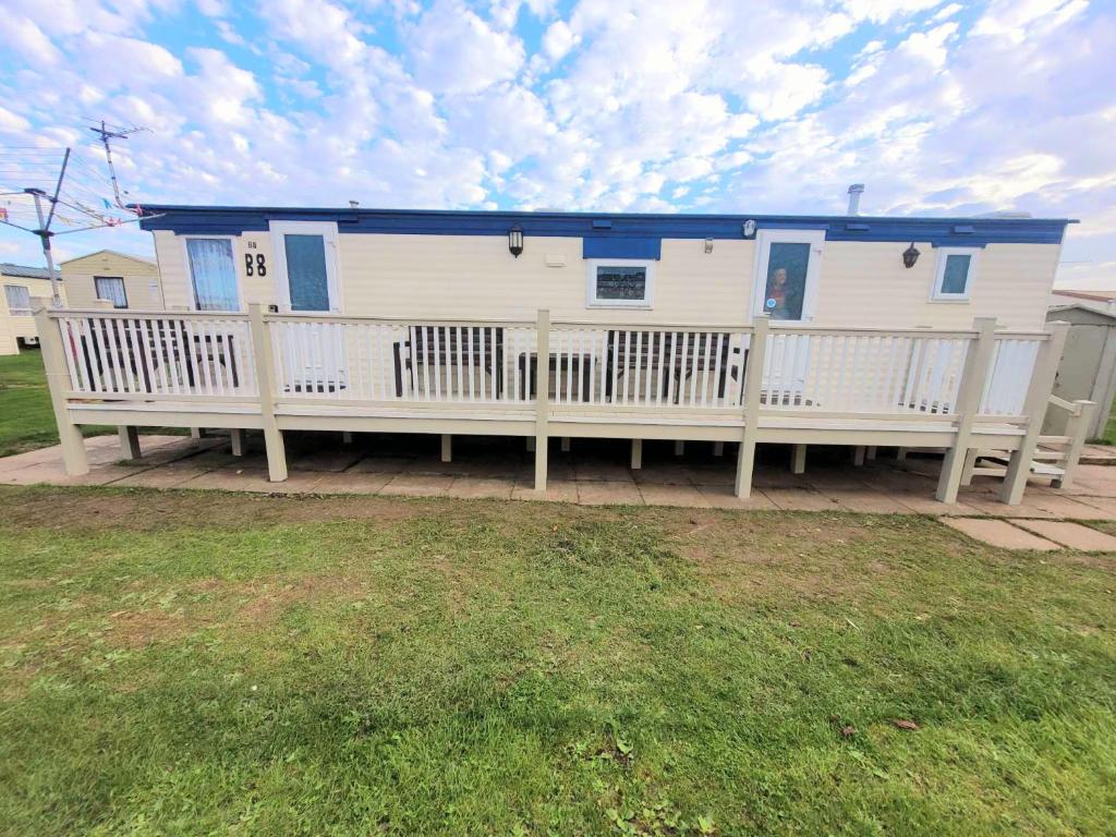 Casa blanca con techo azul y porche en B8 The chase caravan park, caravan ref B 3 Bed 8 Berth, en Ingoldmells