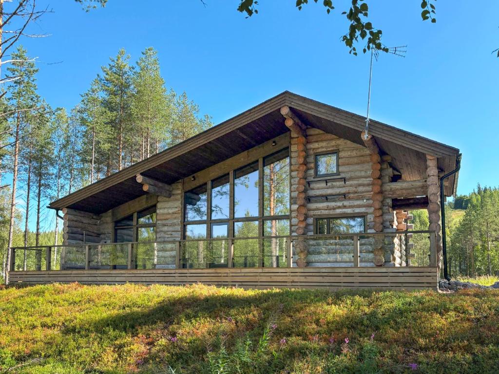 a log cabin in the woods with large windows at Holiday Villa Karhunkelo - sis 4 kpl hissilippuja in Ukkohalla