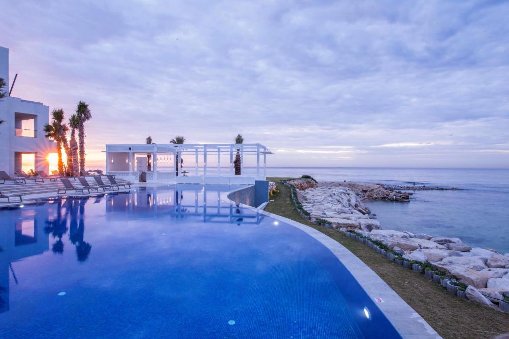 a swimming pool in front of a house and the ocean at La Badira - Adult Only in Hammamet