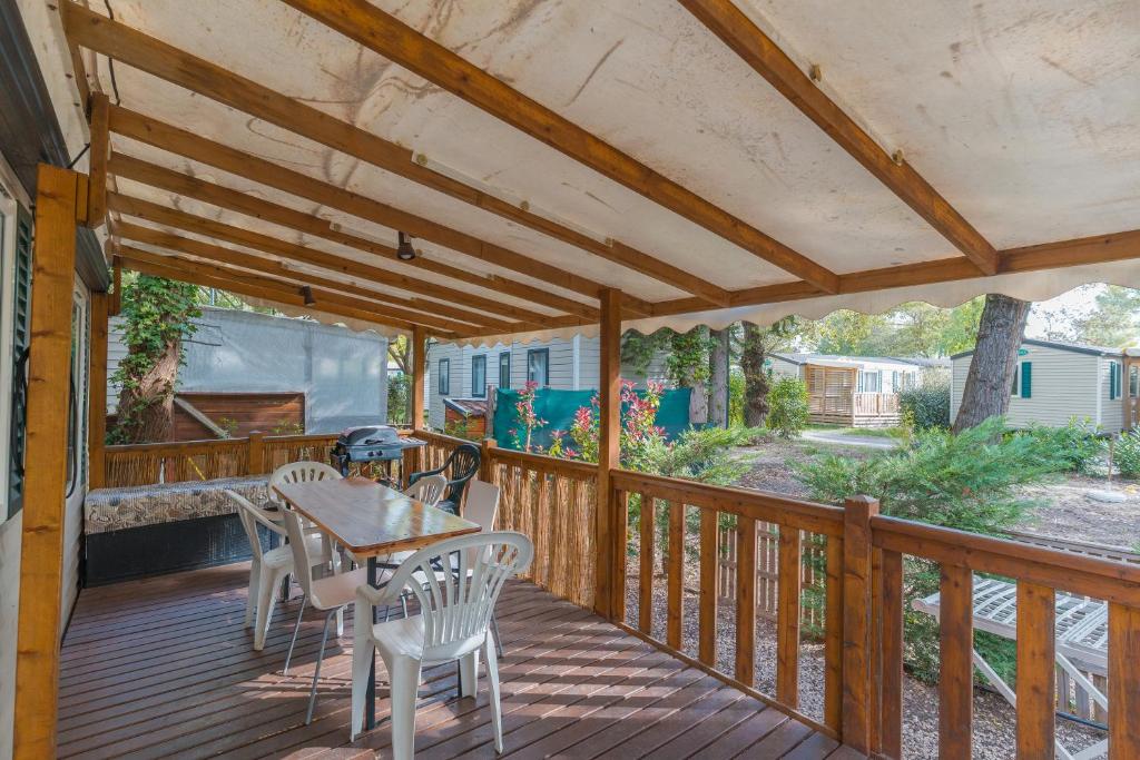 eine Terrasse mit Tisch und Stühlen auf einem Deck in der Unterkunft Mobil-home in La Roque-dʼAnthéron
