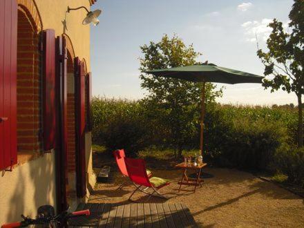 a patio with two chairs and a table with an umbrella at Le Pigeonnier de Roudet in Larrazet