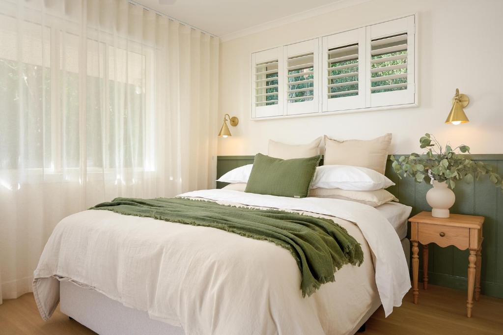 a bedroom with a large bed with a green blanket at Oak Ridge Cottage in Maleny